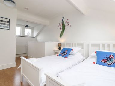 A bedroom with two single beds with butterfly cushions and a peacock wall decal at Snowflake Cottage in Windermere