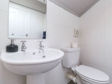 A bathroom with a sink a mirror a toilet and a soap dispenser at Snowflake Cottage in Windermere