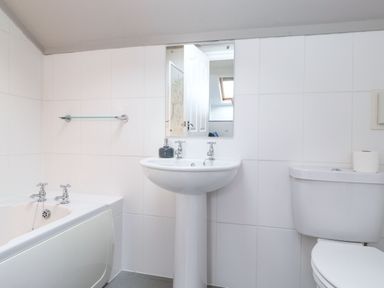 A bathroom with a bathtub sink and toilet at Snowflake Cottage in Windermere