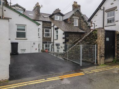 A paved driveway with metal railings beside stone and white houses at Snowflake Cottage in Windermere