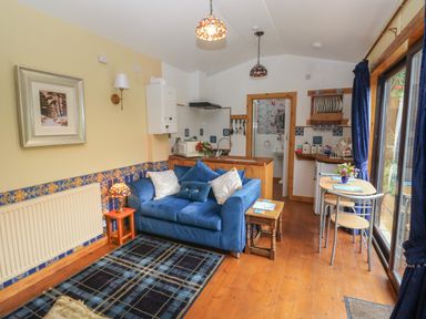 A living room with a blue sofa and dining table next to sliding glass doors at Turnpike Lodge in Brixham