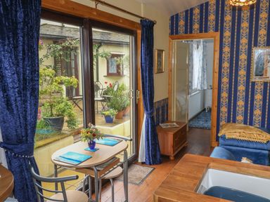 A room with a small table and two chairs near sliding glass doors overlooking a patio with plants at Turnpike Lodge in Brixham