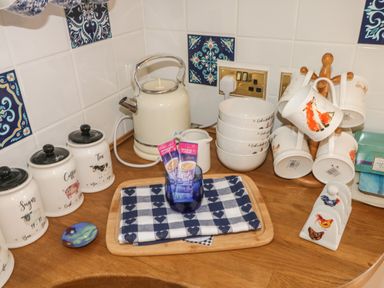 A kitchen counter with a cream electric kettle food canisters and mugs on a mug tree at Turnpike Lodge in Brixham