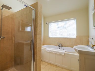 A bathroom with a shower enclosure bathtub sink and window blinds at The Stables at Hall Barn Wattisfield near Walsham-Le-Willows