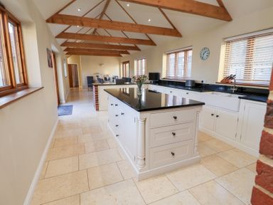 A kitchen with an island and cabinets at The Stables at Hall Barn Wattisfield near Walsham-Le-Willows