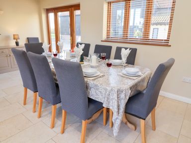 A dining room with a table set for dinner at The Stables at Hall Barn Wattisfield near Walsham-Le-Willows