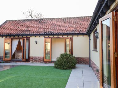 An outdoor area with doors and windows at The Stables at Hall Barn Wattisfield near Walsham-Le-Willows