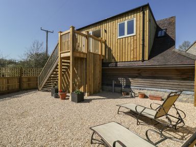 An outdoor area with gravel ground loungers potted plants and a wooden staircase leading to an upper floor at The Attic at Redmond Bottom in Wookey