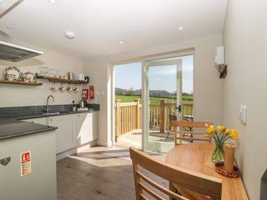 A kitchen with a wooden dining table and chairs and glass door leading to a balcony at The Attic at Redmond Bottom in Wookey