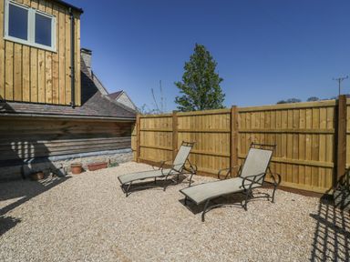 An outdoor patio area with two lounge chairs and a wooden fence at The Attic at Redmond Bottom in Wookey