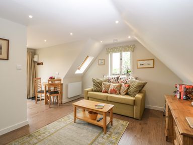 A living room with a sofa, coffee table, and dining table at The Attic at Redmond Bottom in Wookey
