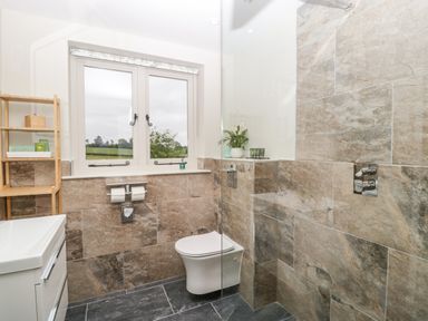 A bathroom with a toilet sink wooden shelf and a window showing outside at The Attic at Redmond Bottom in Wookey