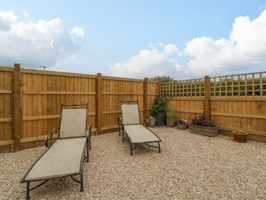 A fenced outdoor area with two lounge chairs and several flower pots at The Attic at Redmond Bottom in Wookey