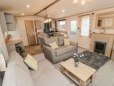A living room and kitchen area with sofas dining table coffee table and fireplace at 20 Wolds View in East Heslerton near West Heslerton