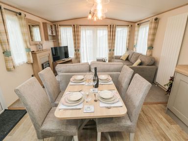 A dining area with a set table for four and a living room with sofas and a television at 20 Wolds View in East Heslerton near West Heslerton