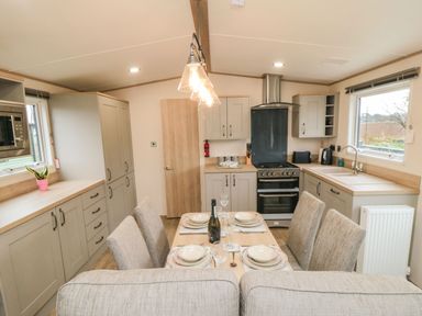 A kitchen and dining area with a set table and beige cabinets at 20 Wolds View in East Heslerton near West Heslerton