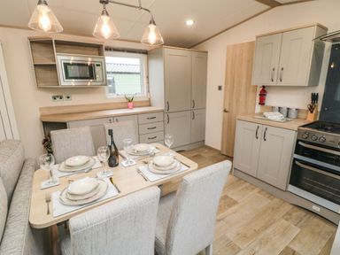 A kitchen with a dining table set for four a microwave oven stove cabinets and a window at 20 Wolds View East Heslerton near West Heslerton