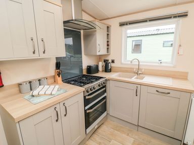 A kitchen with cabinets a stove a sink and a window at 20 Wolds View East Heslerton near West Heslerton