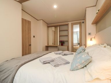 A bedroom with a bed towels on it a dressing table with shelves and a mirror at 20 Wolds View East Heslerton near West Heslerton