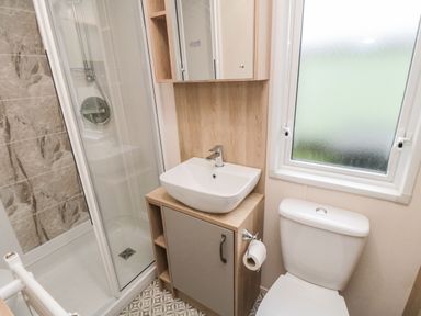 A bathroom with a shower, a sink with cabinet, a toilet, and a frosted window at 20 Wolds View in East Heslerton near West Heslerton
