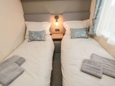A bedroom with two single beds with white bedding and blue floral pillows at 20 Wolds View East Heslerton near West Heslerton