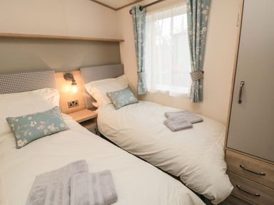 A bedroom with two single beds and floral curtains at 20 Wolds View in East Heslerton near West Heslerton