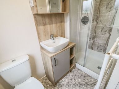 A bathroom with a toilet sink cabinet and a glass shower enclosure at 20 Wolds View East Heslerton near West Heslerton
