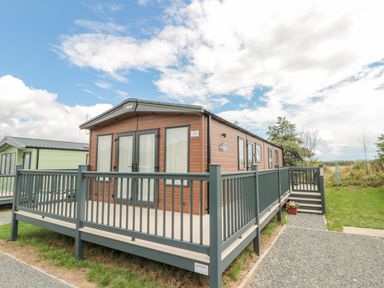 A brown mobile home with a gray deck and railings on a grassy plot at 20 Wolds View East Heslerton near West Heslerton