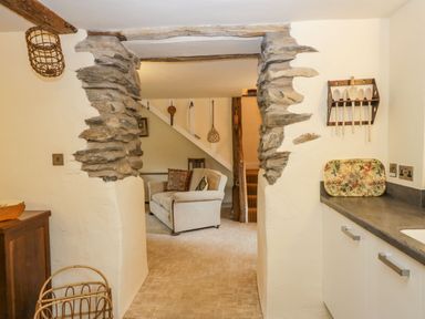 A view through a stone archway into a living area with a sofa and staircase at Myra's View in Newby Bridge