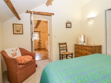A bedroom with a bed a wooden dresser a wooden chair and an armchair at Myra's View in Newby Bridge