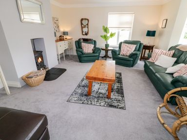 A living room with green leather sofa and chairs wooden coffee table and fireplace at The Glen in Carndonagh County Donegal