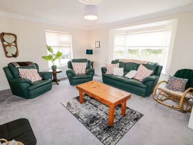A living room with green leather sofas a wooden coffee table and a wicker chair at The Glen in Carndonagh County Donegal
