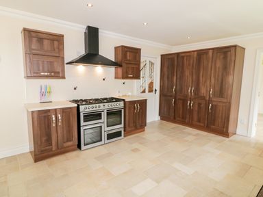 A kitchen with wooden cabinets a gas stove and a range hood at The Glen in Carndonagh County Donegal
