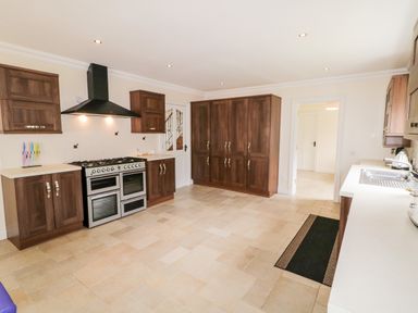 A kitchen with wooden cabinets stainless steel stove and white countertops at The Glen in Carndonagh County Donegal