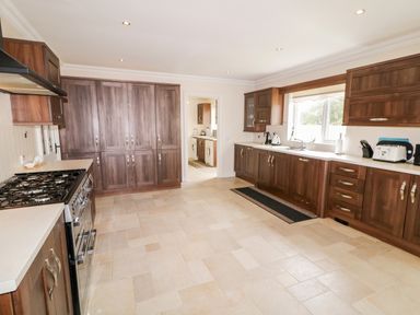 A kitchen with wooden cabinets a stove a toaster and a window at The Glen in Carndonagh County Donegal