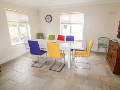 A dining room with a white table and colorful chairs including yellow red purple and green at The Glen in Carndonagh County Donegal