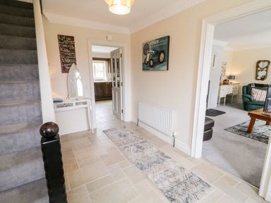 An entryway with tiled floor a staircase a rug a small white table and doors leading to a kitchen and living room at The Glen in Carndonagh County Donegal