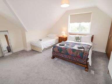 A bedroom with a double bed a single bed a nightstand with a lamp and a standing mirror at The Glen in Carndonagh County Donegal