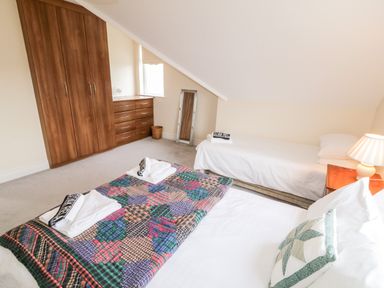 A bedroom with two beds a wooden wardrobe a chest of drawers and a bedside table with a lamp at The Glen in Carndonagh County Donegal