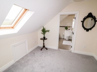A room with a skylight window a small round table with a plant a doorway leading to a bathroom and a wall mirror at The Glen in Carndonagh County Donegal