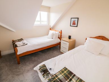 A bedroom with two single wooden beds a nightstand between them and a window on a slanted wall at The Glen in Carndonagh County Donegal