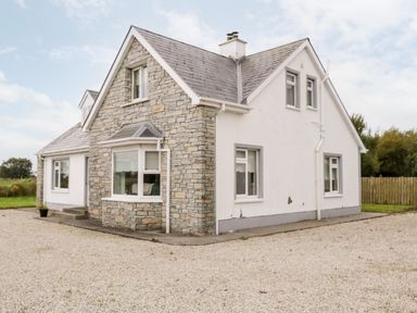 A stone and white plaster house with multiple windows and a gravel driveway at The Glen in Carndonagh County Donegal