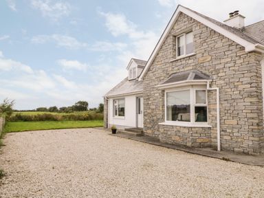 A stone and white house with a gravel driveway and green grass in the background at The Glen in Carndonagh County Donegal