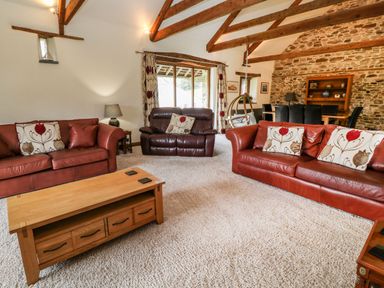 A living room with leather sofas wooden coffee table and exposed wooden beams at Birchenhayes in St Dominick