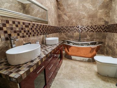 A bathroom with two white vessel sinks on a tiled vanity a copper bathtub and a toilet at Birchenhayes in St Dominick
