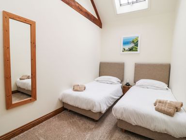 A bedroom with two single beds a wooden framed mirror and a skylight at Birchenhayes in St Dominick