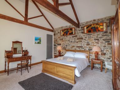 A bedroom with a bed and a wooden wardrobe at Birchenhayes in St Dominick