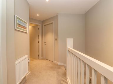 A hallway with two doors a radiator and a white banister at Bruach in Backbarrow