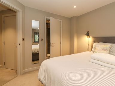 A bedroom with a bed with folded towels a wall lamp and two doors at Bruach in Backbarrow