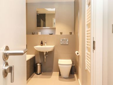A bathroom with a wall-mounted sink toilet and mirror at Bruach in Backbarrow